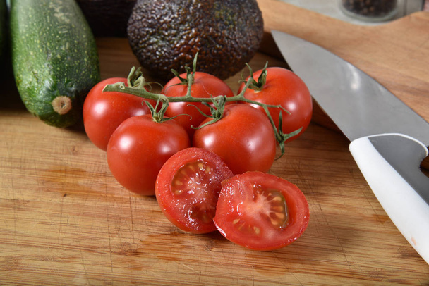 Fresh vine ripened pearl tomatoes on a cutting board with avocado and zucchini - Foto, Imagen