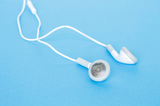 Ohrhörer oder Kopfhörer auf blauem Hintergrund - Foto, Bild
