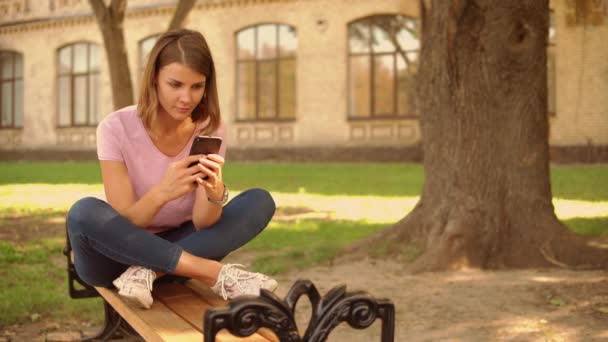 jeune femme messagerie sur mobile près de collège
 - Séquence, vidéo