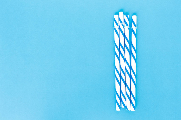 blue striped straws on pink background - Foto, afbeelding