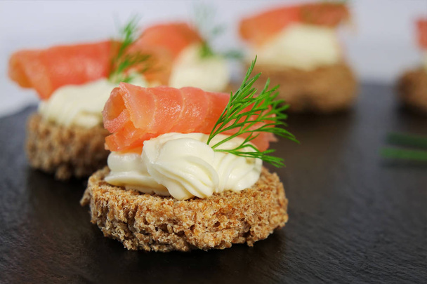 tartine di salmone affumicate con crema di formaggio e aneto su pane marrone su piatto di ardesia nera, dof superficiale
 - Foto, immagini