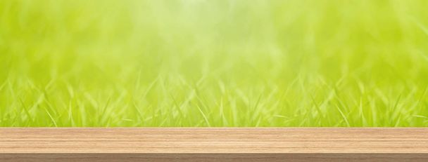Wood table top in front of blur green grass for product and display montage banner size. - Photo, Image