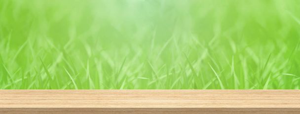 Holz Tischplatte vor unscharfem grünem Gras für Produkt- und Displaymontage Banner Größe. - Foto, Bild