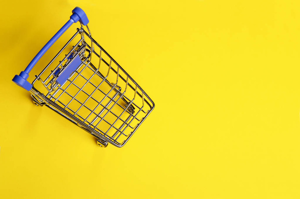 Shopping cart on yellow background - Φωτογραφία, εικόνα