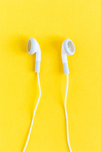 oordopjes of koptelefoons op gele achtergrond - Foto, afbeelding