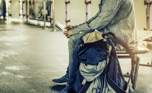 Reizigers Man met rugzak en kaart, kijken tijdens de treinreis op een bankje bij het station, Concept zomer reizen van plan en route met de kaart controleren. - Foto, afbeelding