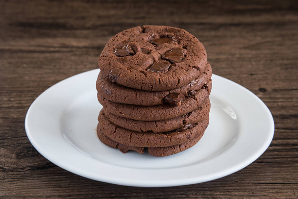 Dark Chocolate Cookies on white plate and wood table. - Photo, Image