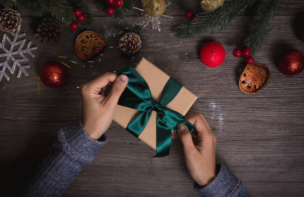 Hand holding Christmas present gift set on wooden table background. - Фото, изображение
