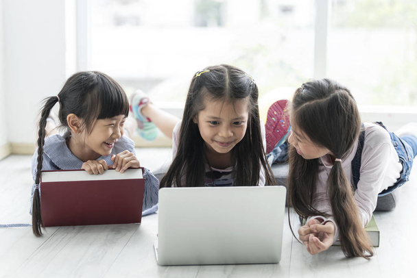 Asiatische Kinder spielen zu Hause mit Laptop. - Foto, Bild