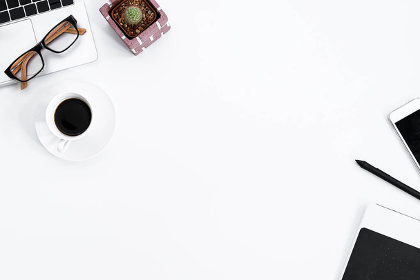 Grafisch ontwerper witte werktafel met computer, cactus, koffie, telefoon en pen voor hard werken in de ochtend met bovenaanzicht. Bureau bovenaanzicht concept. - Foto, afbeelding