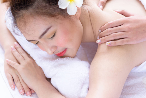 Retrato de hermosas personas asiáticas con vista de cerca y cerrar los ojos y tener masaje en la mano en el salón de spa. Concepto de belleza, salud, spa y relajación
. - Foto, imagen