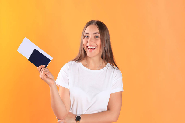 Excited young woman tourist standing isolated on yellow background holding passport with tickets looking camera. - Fotoğraf, Görsel