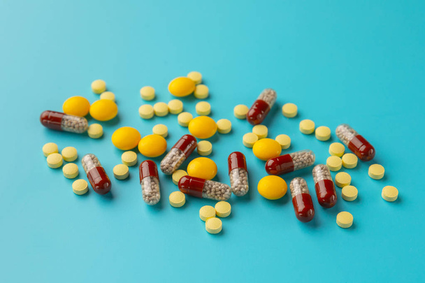 multi-colored pills on a blue background close-up, top view. - 写真・画像