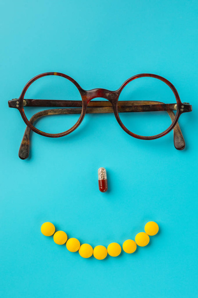 pills. glasses, blue background. Black Eye Glasses with white pills on blue background. - Foto, afbeelding