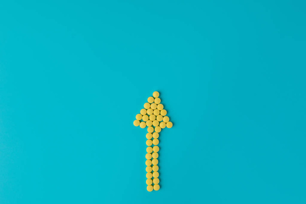 Arrow of yellow pills on a blue background. Flat lay, Top view, - Photo, image