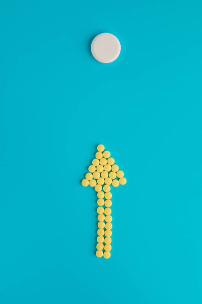 Arrow of yellow pills on a blue background. Flat lay, Top view, - Фото, изображение