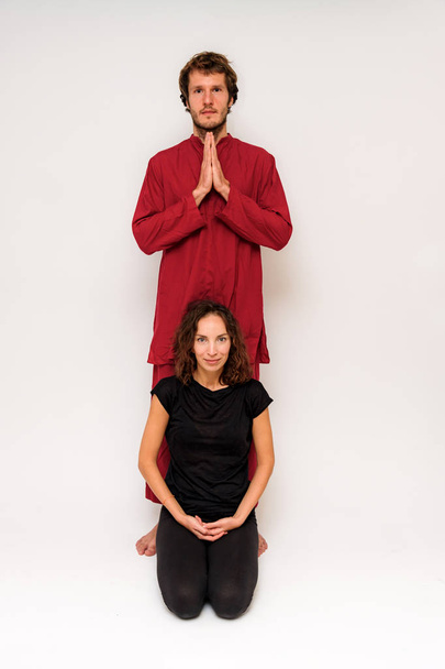 Photo of yoga poses on the floor for two stretching and relaxing on a white background. The man stretches the woman right in front of the camera. - Photo, image