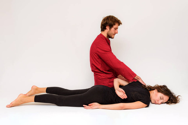 Photo of yoga poses on the floor for two stretching and relaxing on a white background. The man stretches the woman right in front of the camera. - Foto, immagini