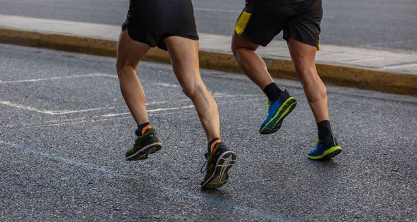 Course de marathon, deux hommes coureurs sur les routes de la ville, détail sur les jambes
 - Photo, image