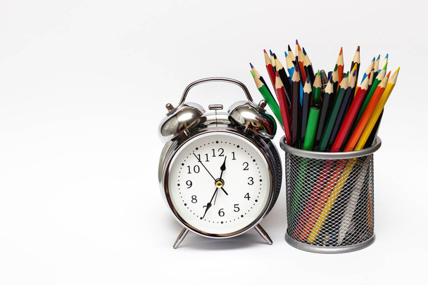 Ébresztőóra, színes ceruza, egy fém pohár. Az idő fogalma, és az üzleti koncepció. - Fotó, kép