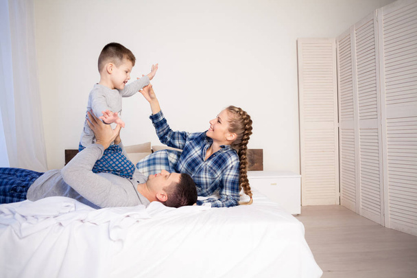 mamá papá y joven hijo en la mañana en la cama jugar una familia riendo
 - Foto, imagen