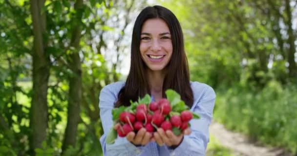 Beautiful young girl holding radishes, in the background of nature. Concept: biology, bio products, bio ecology, grow vegetables, natural pure and fresh product, vegetarians, healthy - Séquence, vidéo