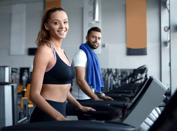 beautiful sports people work on the treadmill in the gym - Fotó, kép