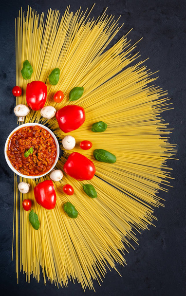 Spaghetti with ingredients for cooking pasta on a black background. Top view. - Photo, image