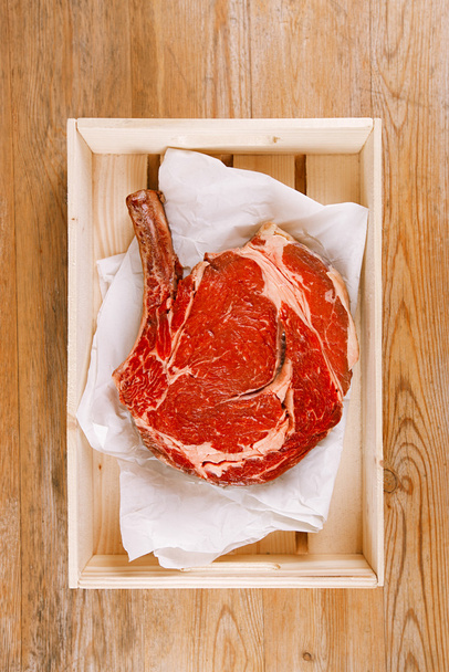 Knochen-Rib-Eye-Steak auf Papier und Holztisch - Foto, Bild