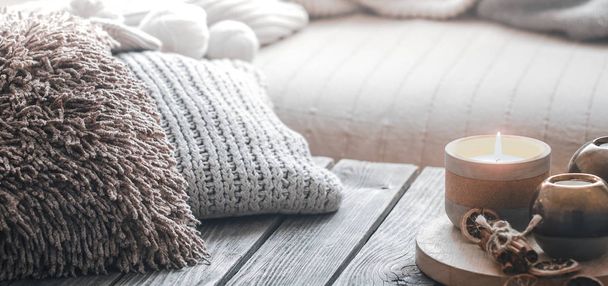 натюрморт з домашнього інтер'єру на дерев'яному тлі зі свічкою та подушками, концепція домашнього комфорту
 - Фото, зображення