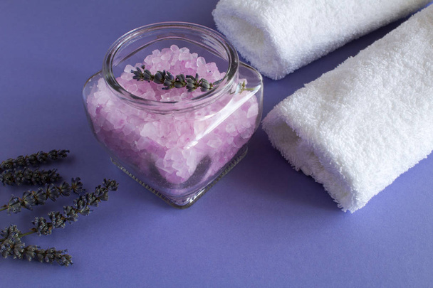 Lawendowy soli w szkło słój i białe ręczniki na fioletowym tle - Zdjęcie, obraz
