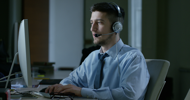 Müşteri Hizmetleri veya bazı Havaalanı kontrol kulesi istasyonunda çalışan genç bir adam, bir gülümseme müşterilere telefon aramaları ve gündüz cevaplar. - Video, Çekim