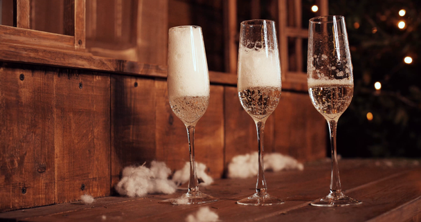 Glazen champagne staande op de achtergrond van een wazig kamer met een versierde kerstboom. - Video