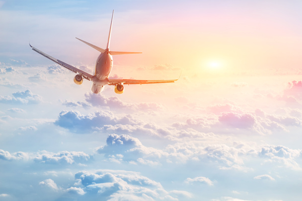 Flugzeug fliegt über schöne flauschige Wolken bei Sonnenuntergang. Reise- und Urlaubskonzept. - Foto, Bild