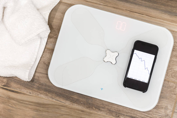Smart scale standing on floor connected by bluetooth to smartphone - Photo, Image