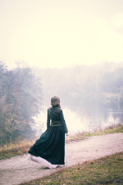 Tyttö seisoo kalliolla tuulisella säällä.
 - Valokuva, kuva