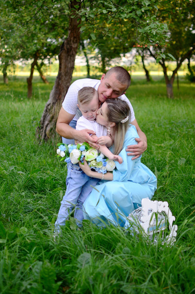 Familia feliz juntos en el jardín / parque de verano. Padre abraza a su hijo y a su esposa. Foto al aire libre
 - Foto, Imagen