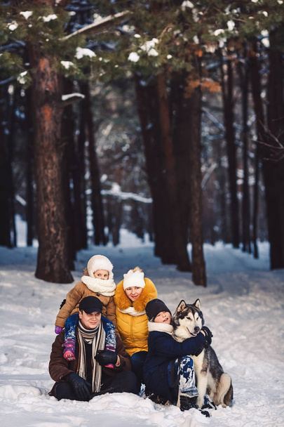 Happy european young family with big dog posing against winter pine forest - Photo, Image
