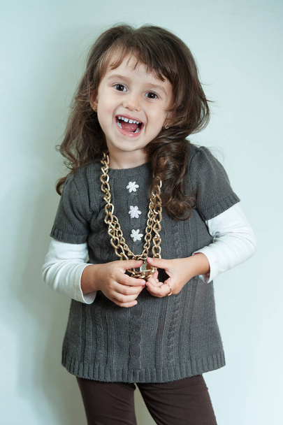 Ευτυχισμένο παιδί κοριτσάκι με χρυσή αλυσίδα σε λευκό φόντο - Φωτογραφία, εικόνα
