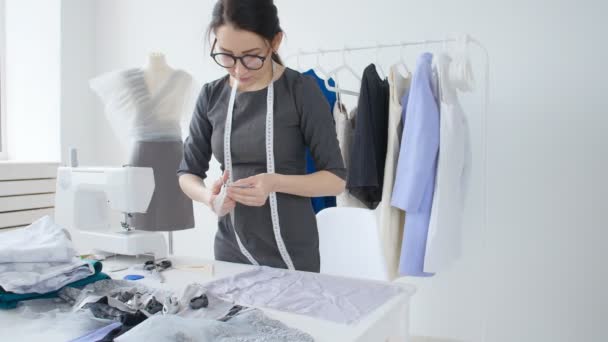 concept van kleine bedrijven en kleine productie. Jonge mooie naaister vrouw naait kleren in de werkplaats - Video