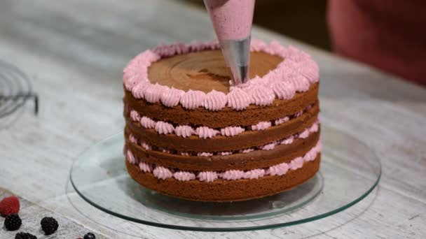 Βήμα-βήμα. Baker συναρμολόγηση ένα κέικ σοκολάτας με γλάσο buttercream πολύχρωμο. - Πλάνα, βίντεο