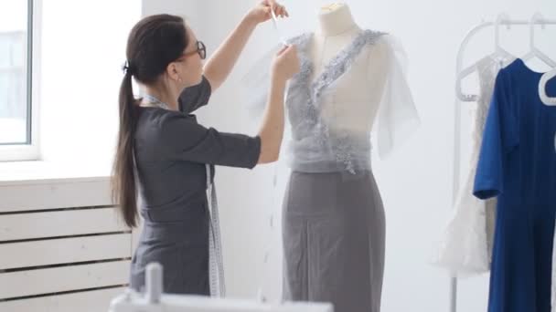 Koncepcja produkcji małych i małych firm. Kobieta młody ładny krawcowej szyje ubrania w warsztacie - Materiał filmowy, wideo