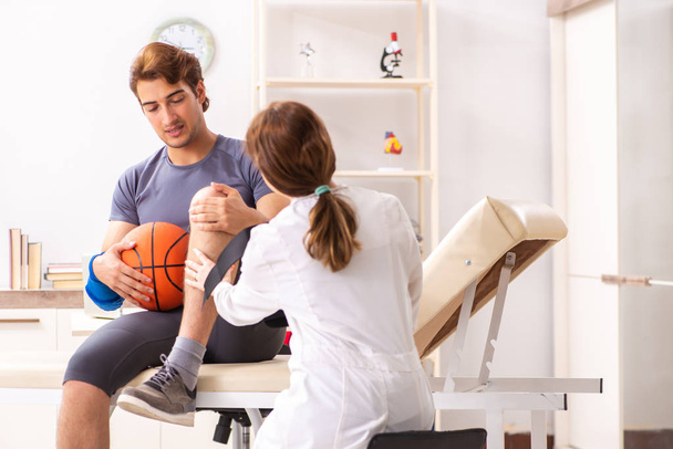 Guapo jugador de baloncesto visitando médico traumatólogo femenino
 - Foto, Imagen