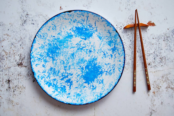 Assiette de service en céramique peinte à la main bleue avec baguettes en bois sur le côté
 - Photo, image