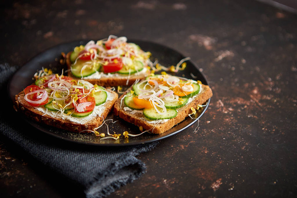Gezonde toastjes met komkommer, tomaten en gemalen feta en radijs spruiten - Foto, afbeelding