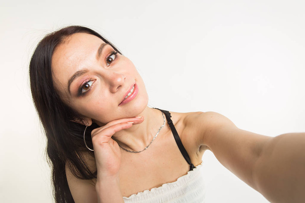 Close-up van jonge mooie vrouw nemen selfie op witte achtergrond - Foto, afbeelding