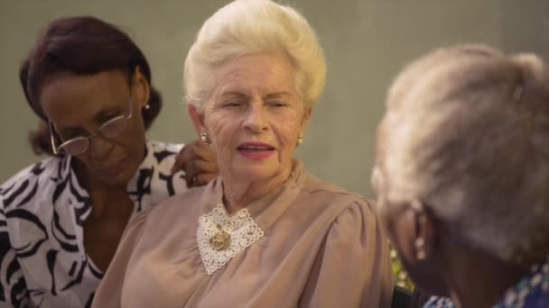 Gruppe fröhlicher älterer afrikanisch-amerikanischer und kaukasischer Freundinnen im Gespräch und auf Bank im Park sitzend - Filmmaterial, Video