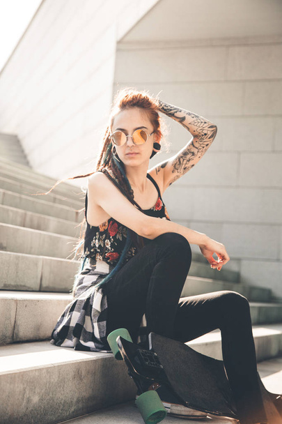 young girl with tattoo and dreadlocks sitting on the steps. - Zdjęcie, obraz