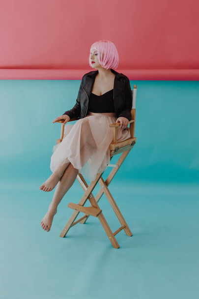 Beautiful young woman with pink hair in director chair - Fotó, kép