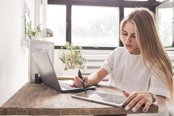 Young business woman working at home behind a laptop and tablet. Creative Scandinavian style workspace - Foto, immagini